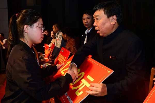 一定发集团董事长李安平向受助学子发放助学金